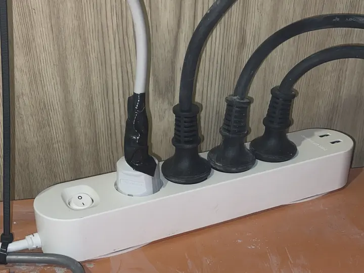 Mehrfachsteckdose auf dem Boden, ein Stecker mit Isolierband umwickelt